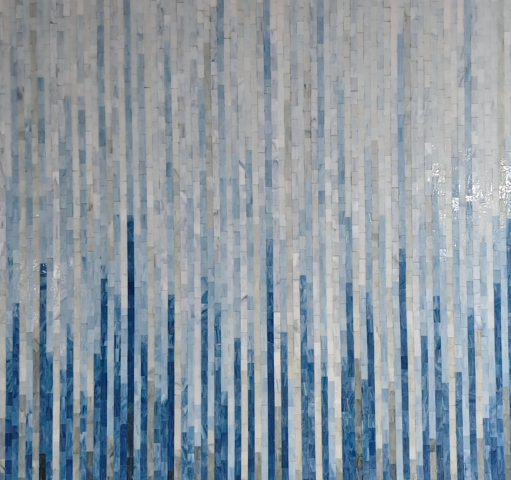 Individual blue and pale mosaic tiles forming an abstract color gradient