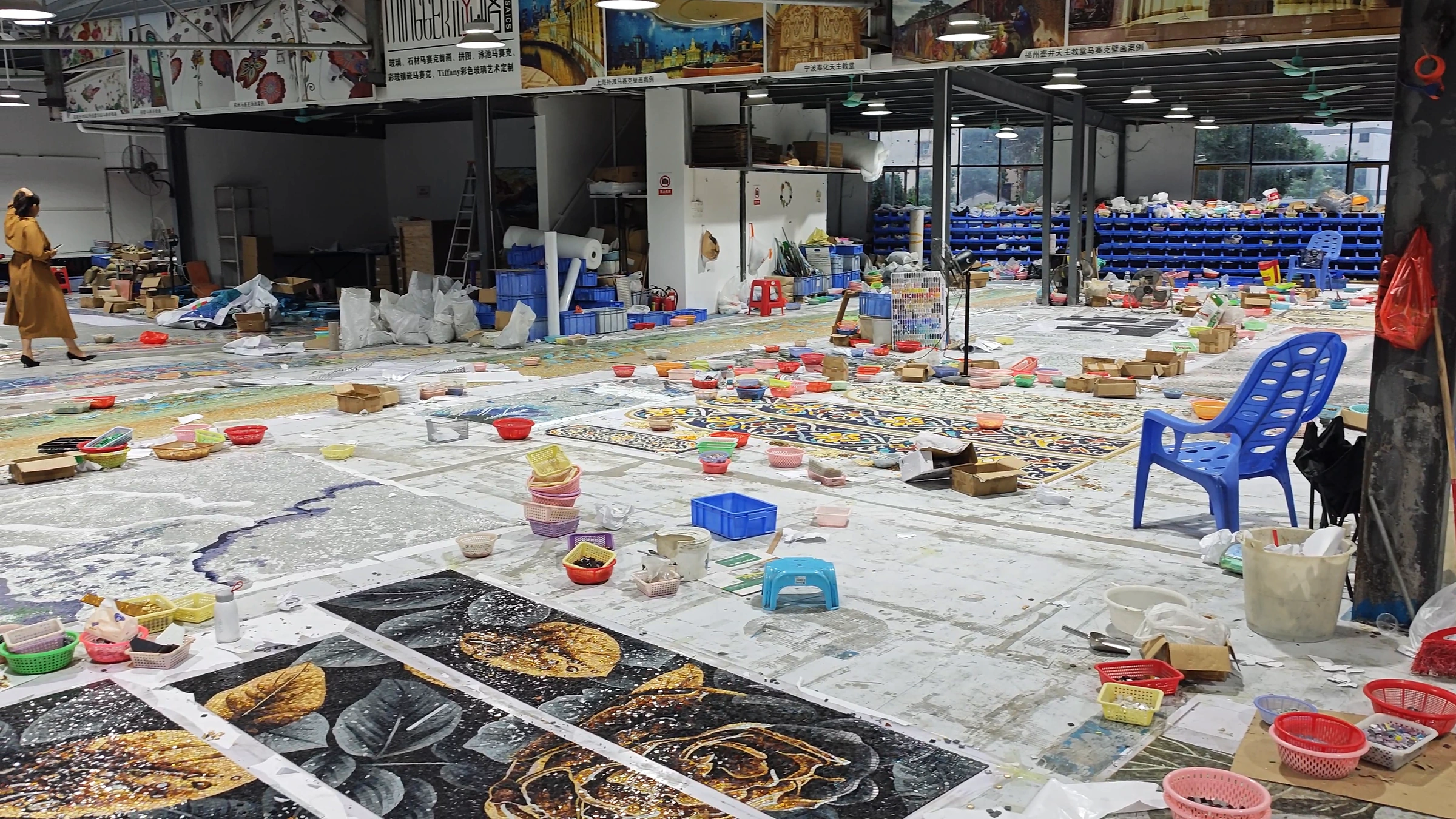Mosaic workshop with artisans, work tables and a large artwork laid out on the floor